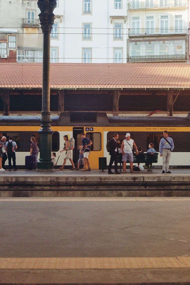 People walking at Sao Bento station, Porto, Portugal with a train in the background.