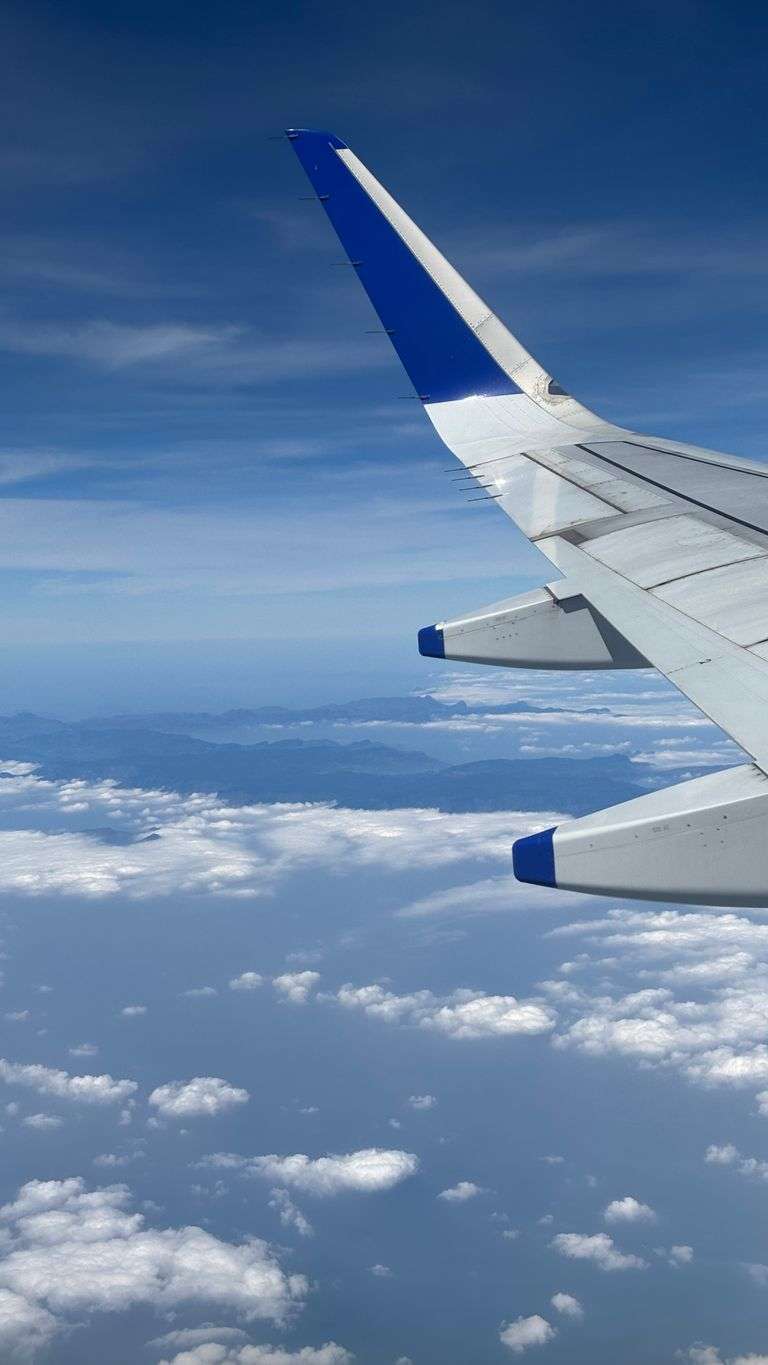 A breathtaking view from an airplane mid-flight, showcasing blue skies and white clouds.