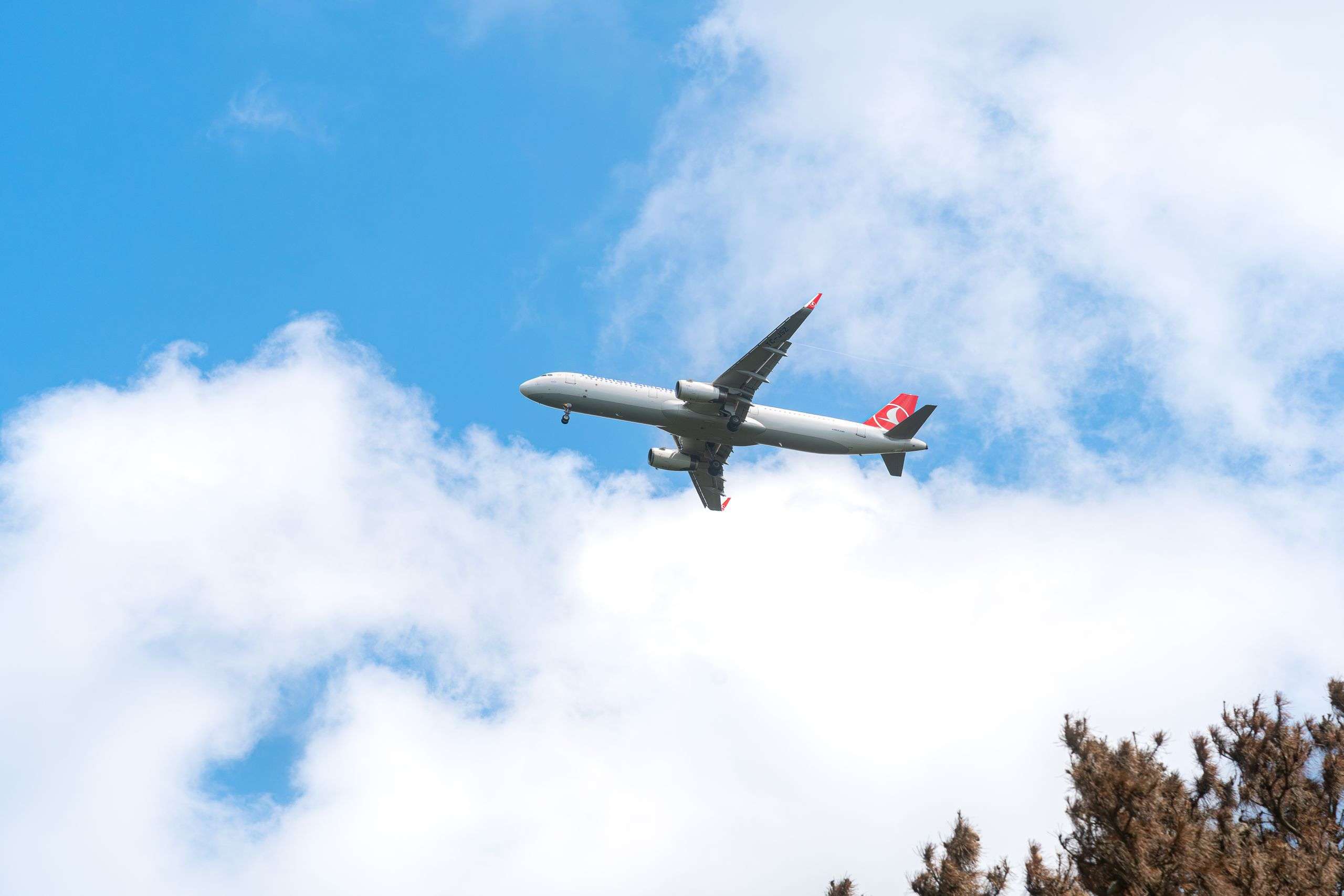 A commercial airplane glides through a clear blue sky with scattered clouds, capturing the essence of aviation travel.