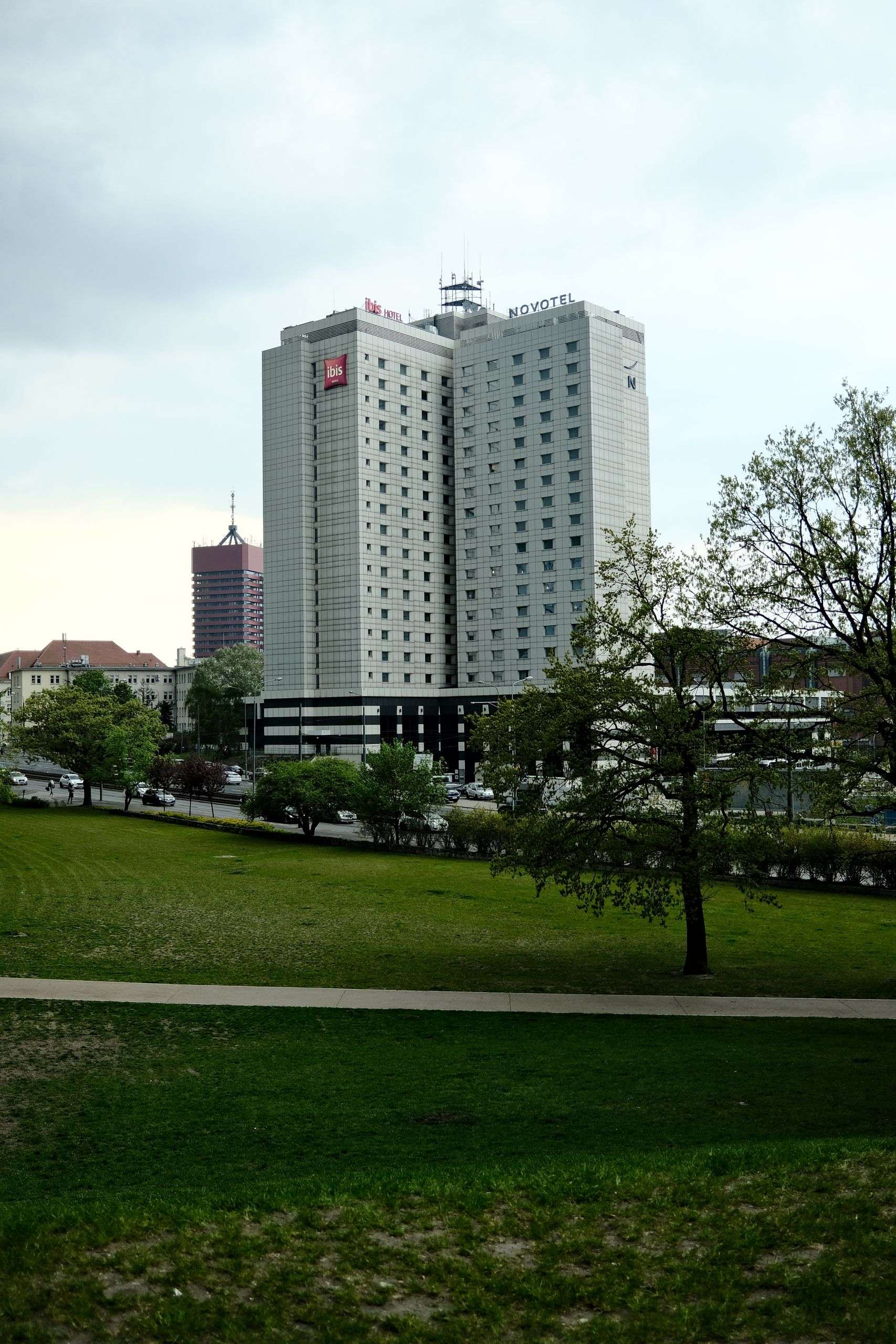 Contemporary hotel buildings surrounded by urban park area on a cloudy day.