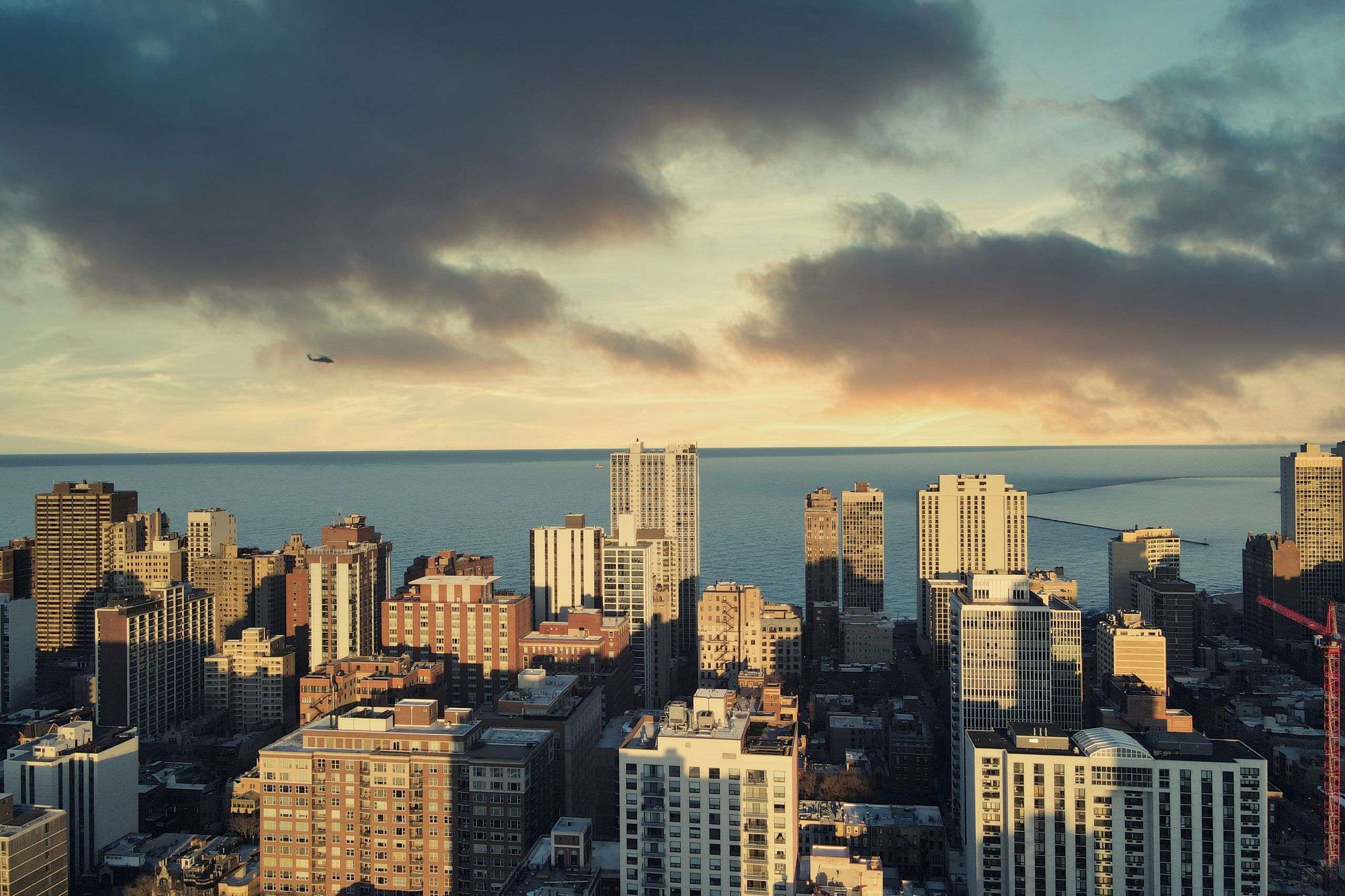 Stunning aerial view of Chicago buildings with Lake Michigan during sunset, clouds enhancing city charm.