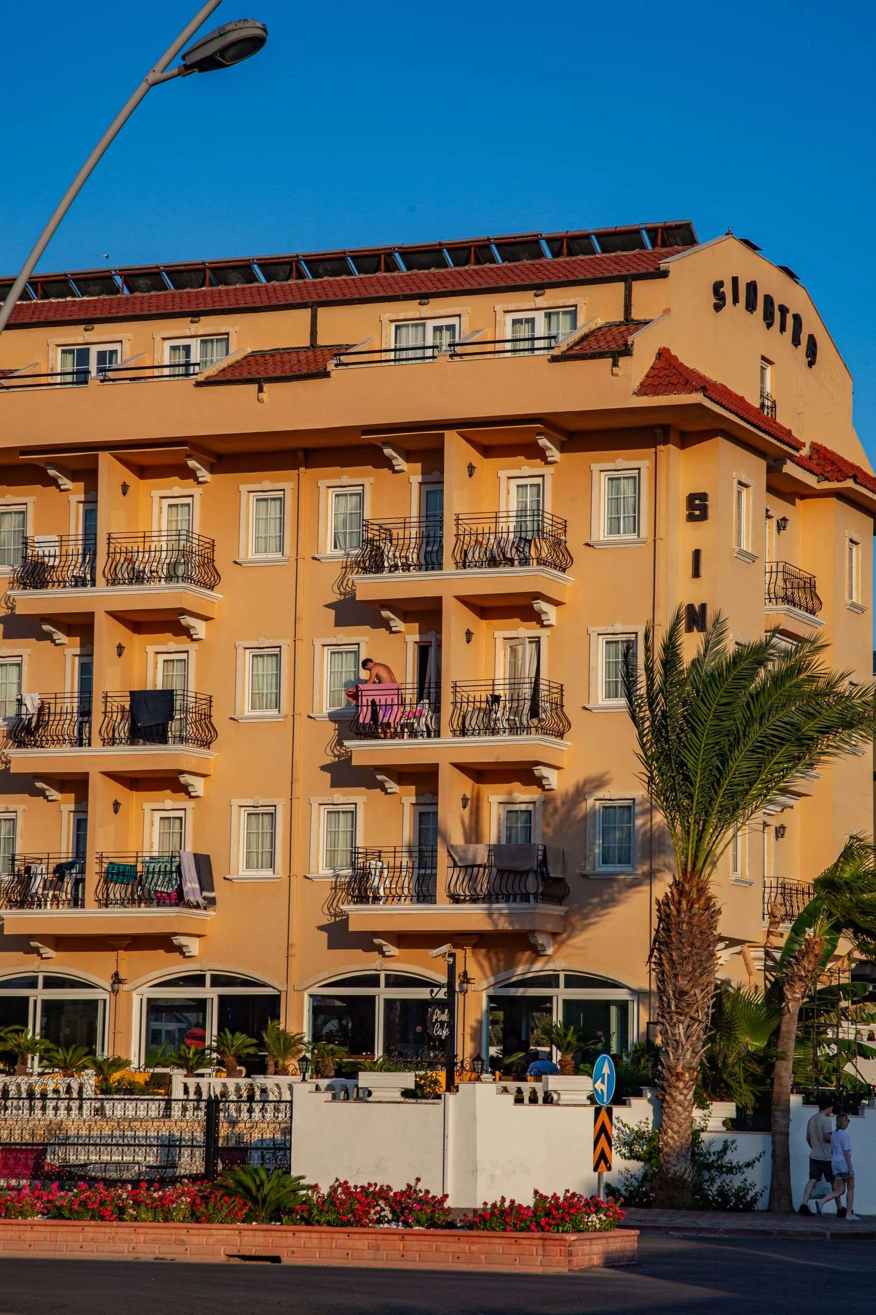 Warm sunset light on a Mediterranean hotel with a palm tree and clear sky.